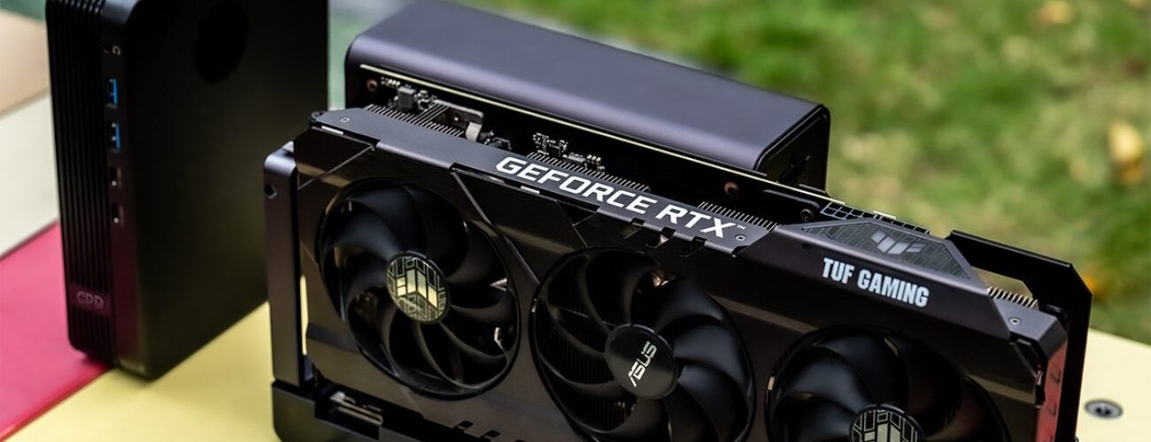Dock eGPU GPD G2 avec une carte graphique ASUS TUF Gaming GeForce RTX installée, montrant le connecteur MCIO et les ports de connectivité sur une table colorée.