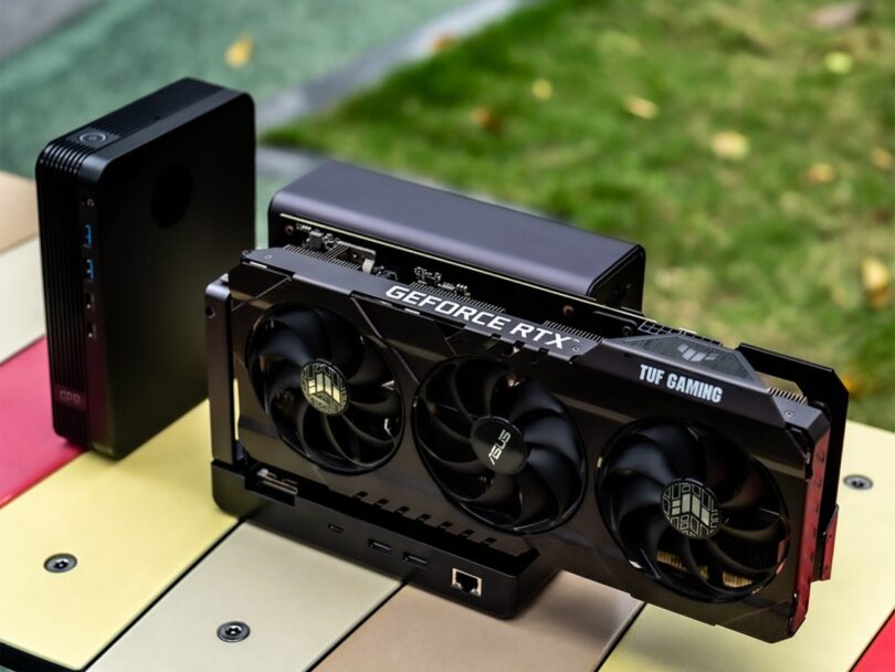 Dock eGPU GPD G2 avec une carte graphique ASUS TUF Gaming GeForce RTX installée, montrant le connecteur MCIO et les ports de connectivité sur une table colorée.