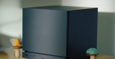 Image conceptuelle générée par IA d'un mini-PC Valve compact et élégant, positionné sur un bureau en bois. L'appareil est un cube noir mat aux lignes épurées, illustrant l'esthétique possible de la nouvelle console de salon de l'entreprise.