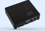 Vue d'angle d'un mini-PC industriel Waveshare CM5-ETH-RS485-4G-BASE noir, montrant les ports d'E/S : deux ports Ethernet (GbE et 2.5GbE), un port HDMI, des ports USB, un port USB Type-C, un slot TF Card et les indicateurs LED de statut, sur un fond bleu clair.