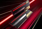 Deux modules de mémoire RAM DDR5 ASUS ROG Certified haut de gamme de couleur noire et or avec éclairage LED rouge, affichant le logo "20th Anniversary" et des coordonnées géographiques.