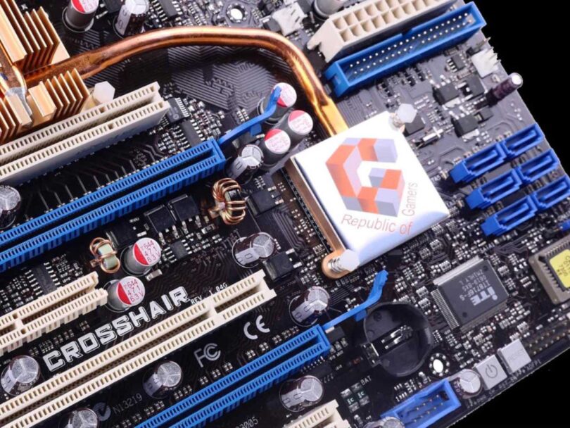 Carte mère Asus ROG Crosshair originale de 2006 vue en gros plan avec son dissipateur cuivre massif, slots PCIe bleu et blanc, condensateurs et chipset estampillé Republic of Gamers, source du design relancé en 2026.