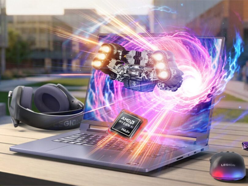 Ordinateur portable gaming Lenovo Legion 7a violet ouvert sur une table en extérieur, affichant une explosion d'effets visuels et un vaisseau spatial sortant de l'écran. Un processeur AMD Ryzen AI Max+ est mis en avant avec des effets de lumière, accompagné d'un casque et d'une souris Legion.