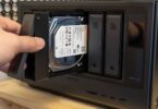 Main d'un utilisateur insérant un tiroir de disque dur Seagate IronWolf 4 To dans la baie d'un NAS multi-baies Ugreen, opération d'extension de stockage NAS en cours.