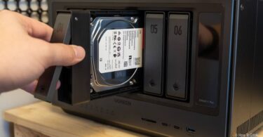 Main d'un utilisateur insérant un tiroir de disque dur Seagate IronWolf 4 To dans la baie d'un NAS multi-baies Ugreen, opération d'extension de stockage NAS en cours.
