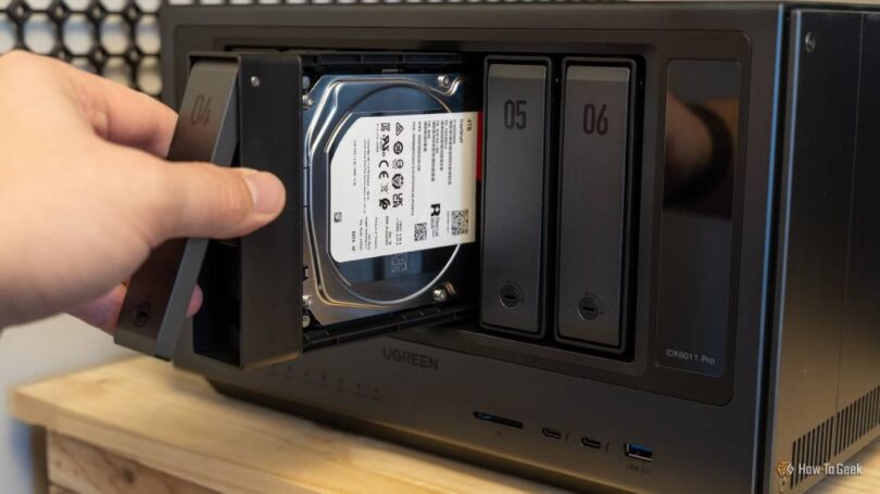 Main d'un utilisateur insérant un tiroir de disque dur Seagate IronWolf 4 To dans la baie d'un NAS multi-baies Ugreen, opération d'extension de stockage NAS en cours.