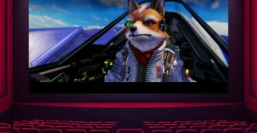Vue d'une salle de cinéma vide, tous les sièges rouges sont inoccupés, faisant face à un grand écran lumineux projetant une scène du film Star Fox avec le personnage Fox McCloud dans son cockpit Arwing.