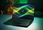 Ordinateur portable gaming Razer Blade 18 modèle 2026 ouvert sur une table, affichant un fond d'écran abstrait vert et le logo de la marque, avec son clavier rétroéclairé RGB actif.