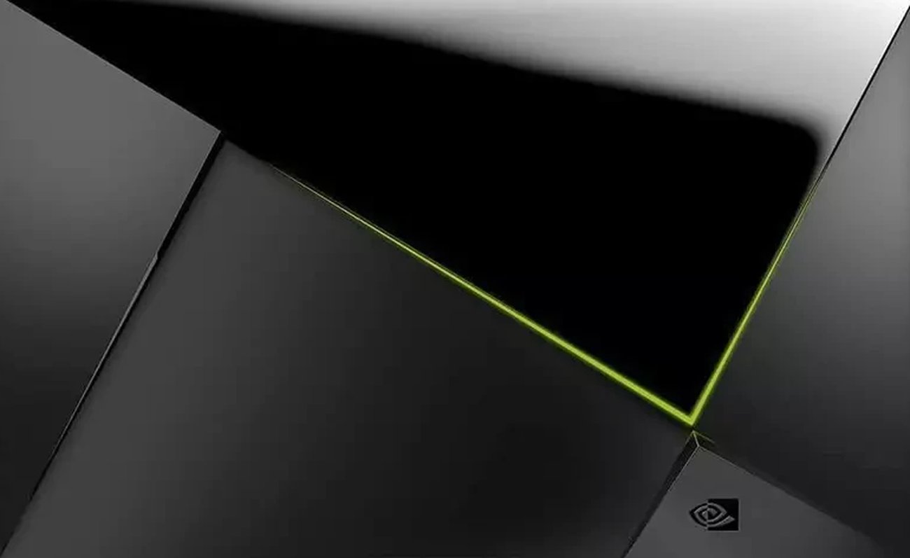Vue de face rapprochée de la Nvidia Shield TV Pro montrant ses facettes triangulaires noires mates et brillantes, le liseré LED vert qui les sépare et le logo NVIDIA dans l'angle inférieur droit.