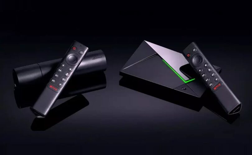 Nvidia Shield TV Pro et Shield TV posées sur fond noir avec leurs télécommandes, la Pro et son liseré vert à droite, le modèle cylindrique à gauche, illustrant la hausse de prix de 2026.